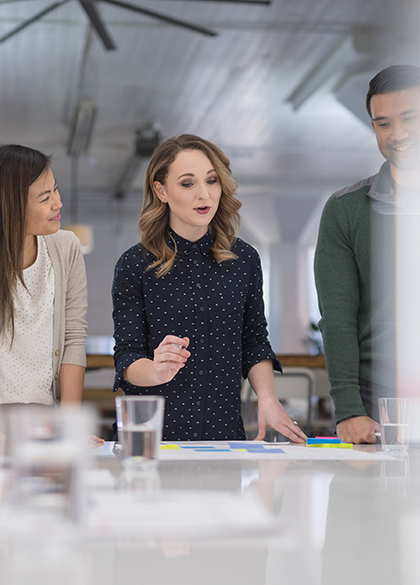 A mixed-ethnic group of business colleagues sign paperwork at the conference table